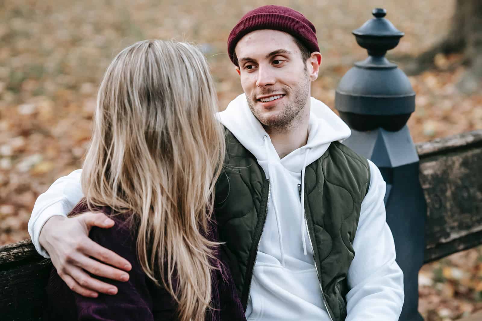 hombre sonriente abrazando a su novia y hablando en el banco