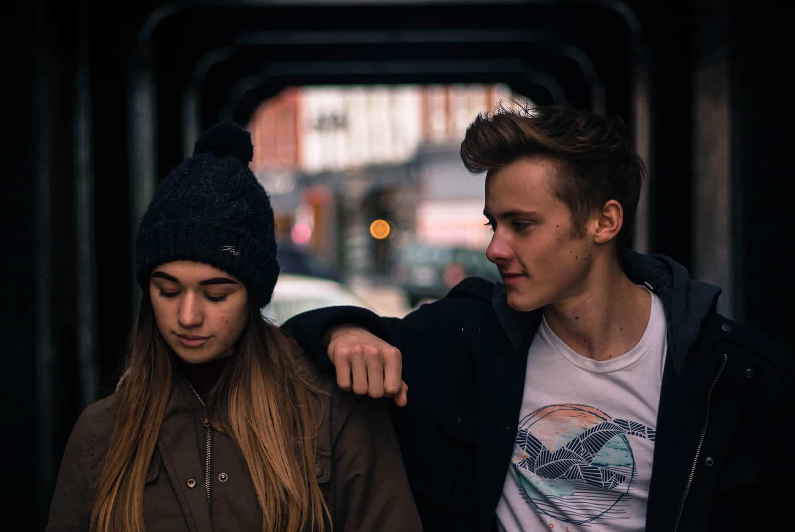 smiling young man looking at his girlfriend and leaning his hand on her shoulder