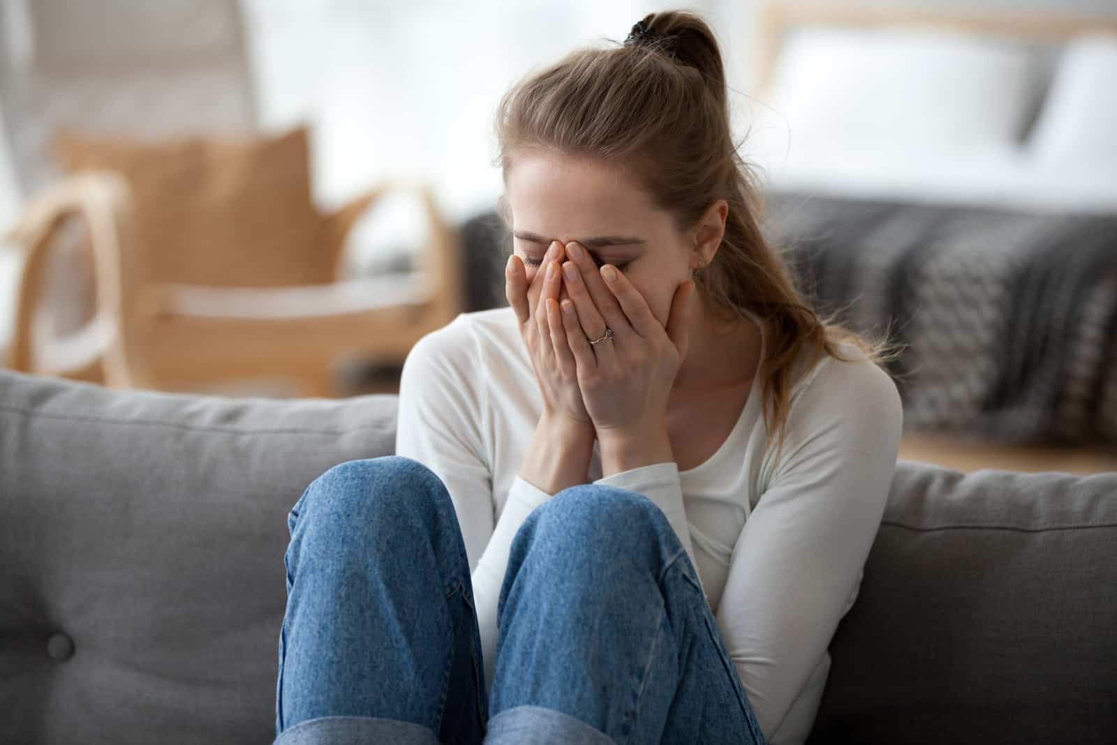woman crying while sitting on sofa