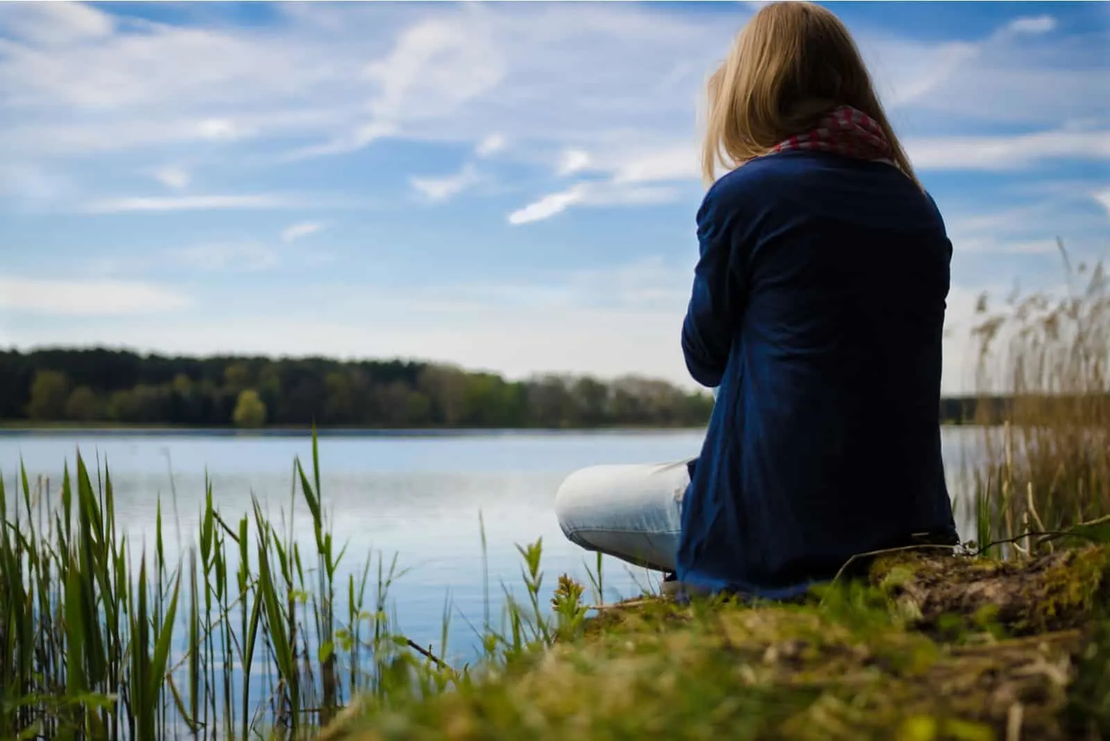 woman in blue cardigan sitting near lake