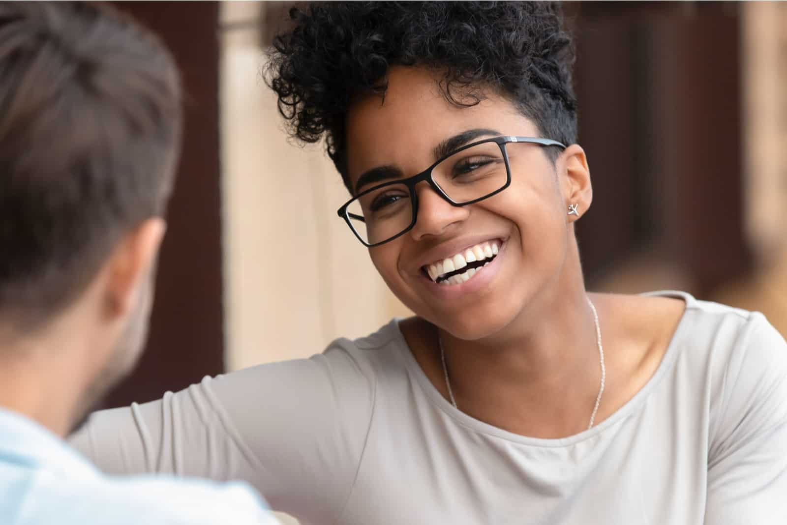 woman with curly hair smiling while looking at man