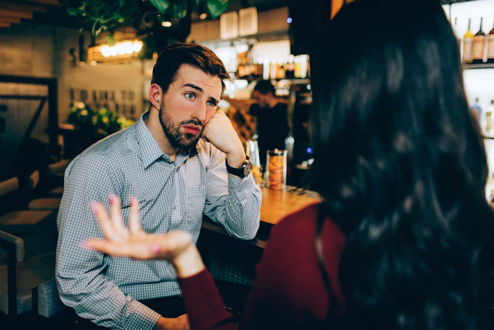 mulher a falar com um homem sentado num bar