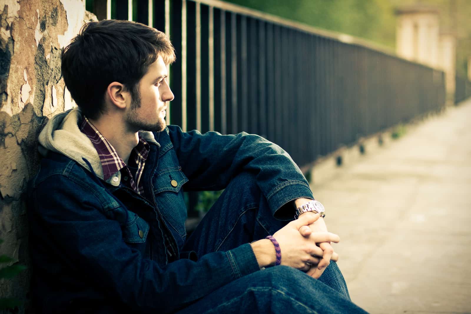 young man sitting on the bridge and looking away