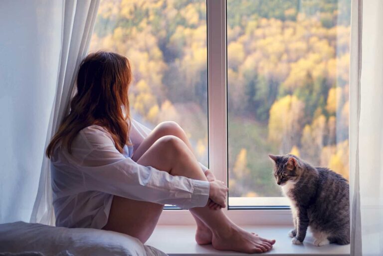 a sad woman sits by the window