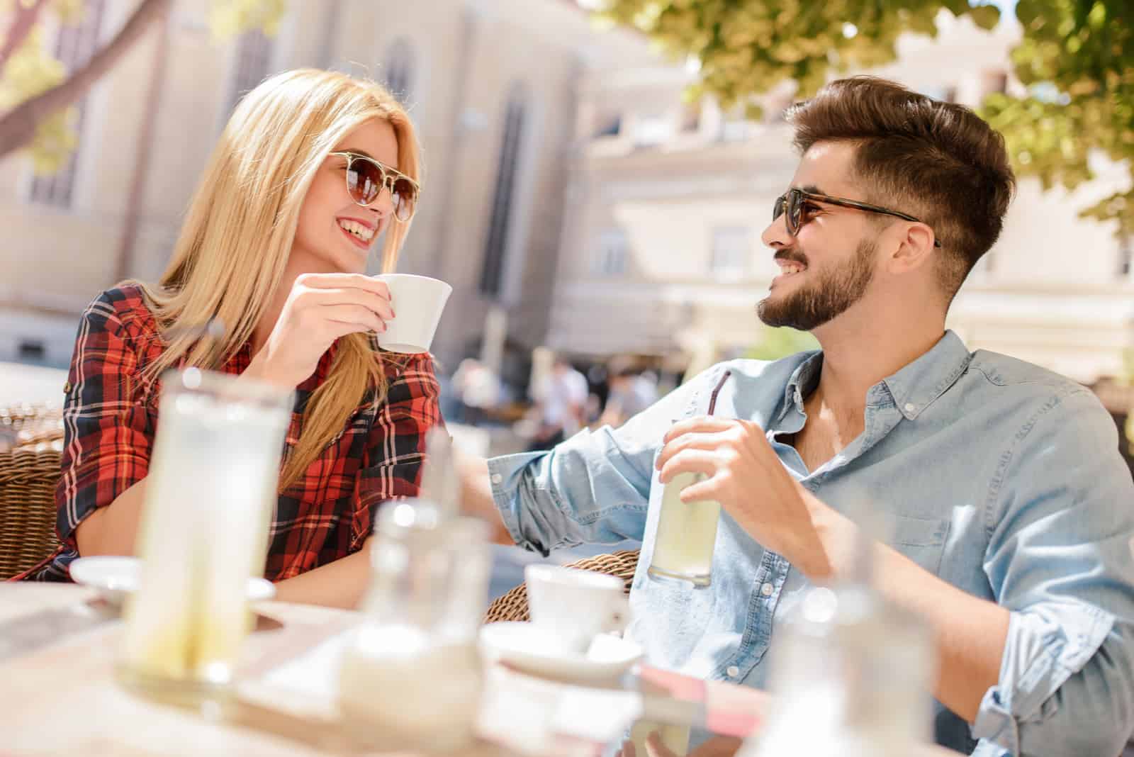 a smiling man and woman sit outdoors and talk