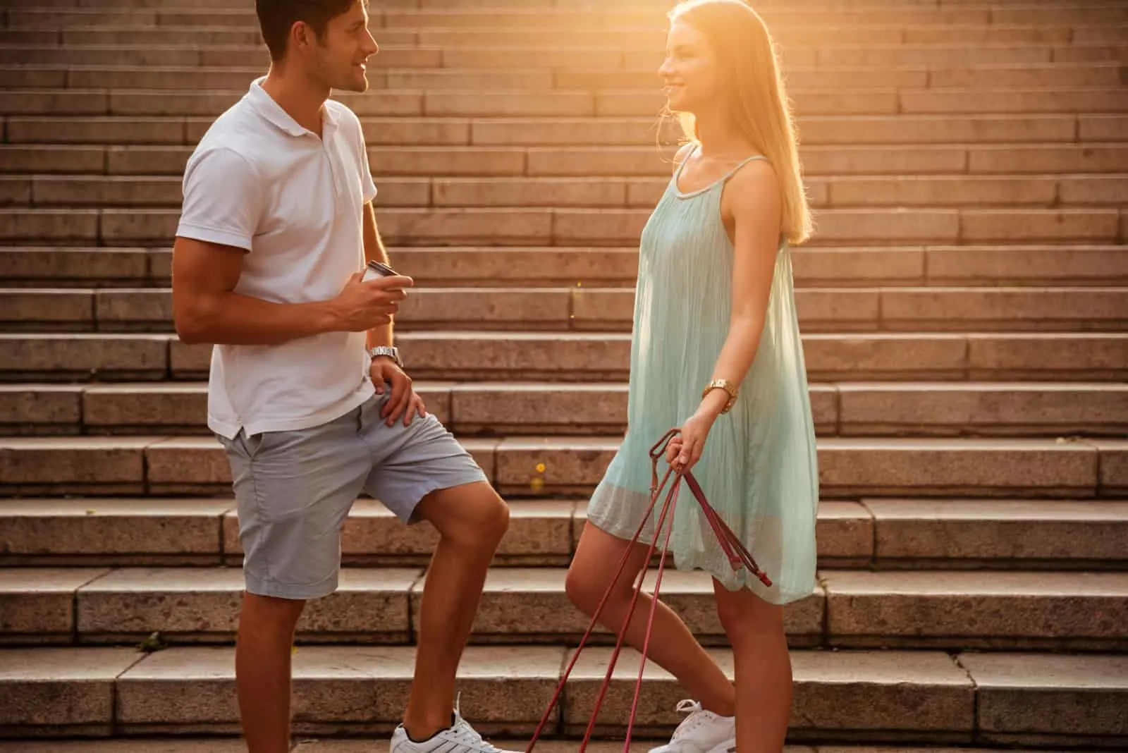 a smiling man and woman stand on the stairs and talk