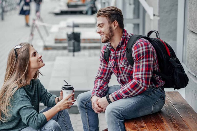 a man sits on a bench and talks to a woman