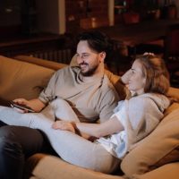 smiling couple sitting on the couch watching movie