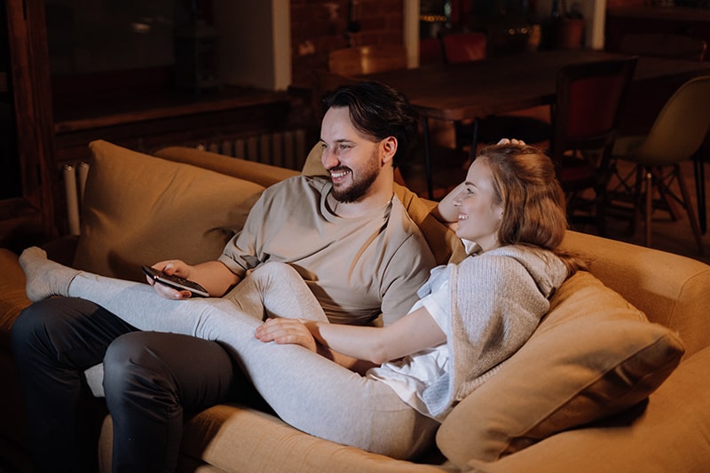 smiling couple sitting on the couch watching movie
