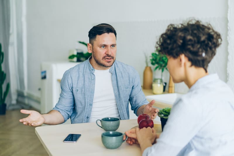 Annoyed man husband yelling drinking coffee with his wife