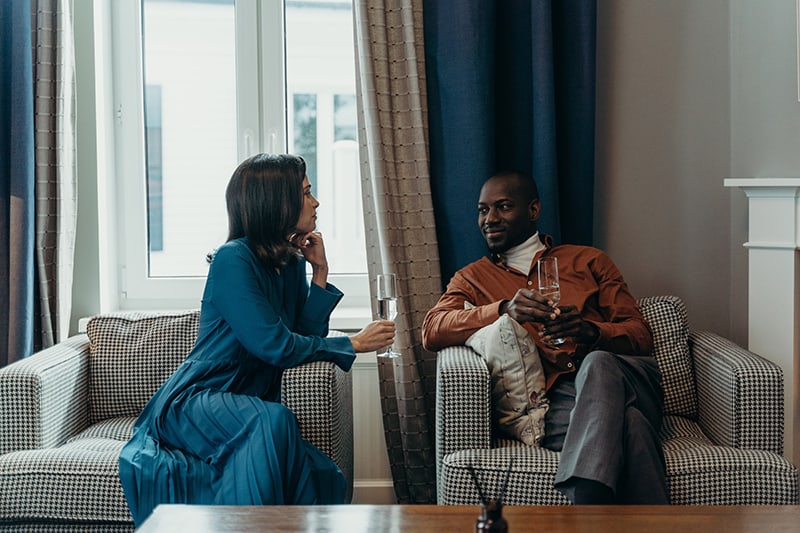 a man and a woman looking each other while drinking champagne