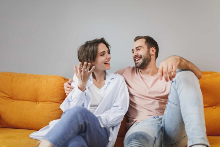 a man and a woman sit on the couch and talk