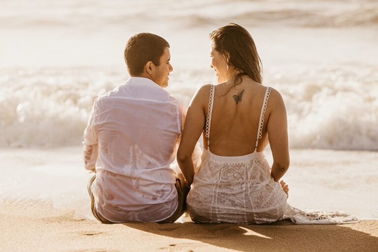 pareja sentada en la playa al atardecer