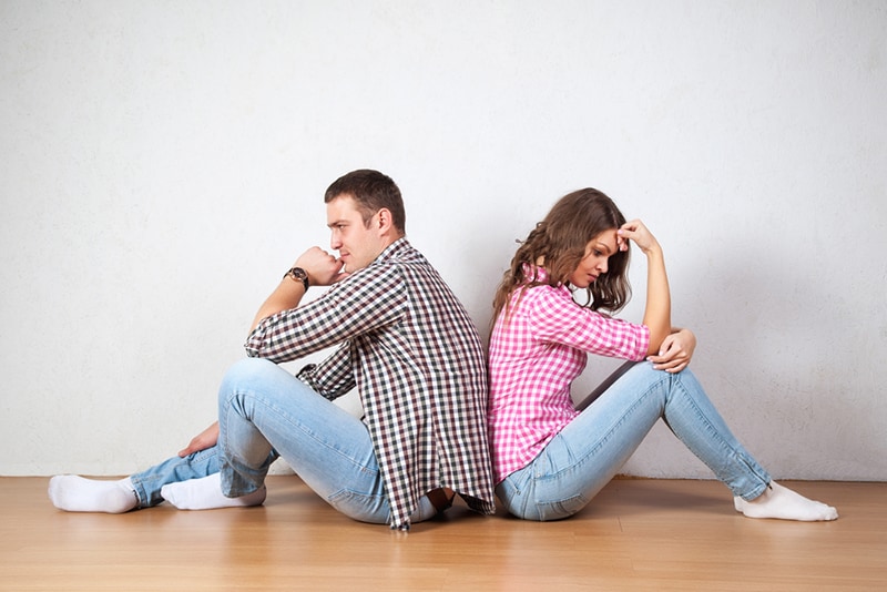 Couple sitting with their backs turned on the floor in apartment