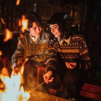 smiling couple sitting near the fireplace in yard