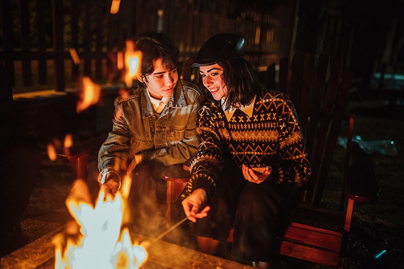 smiling couple sitting near the fireplace in yard