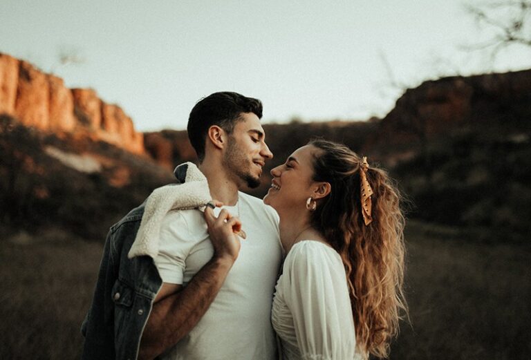 una mujer sonriente mirando a un hombre a los ojos a punto de besarse