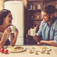 a smiling man and woman sit at a table and have breakfast