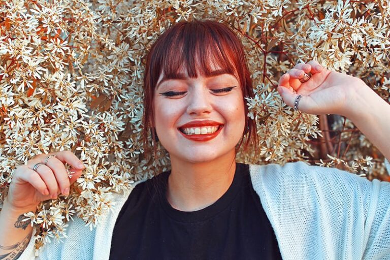 a smiling woman surrounded with white flowers