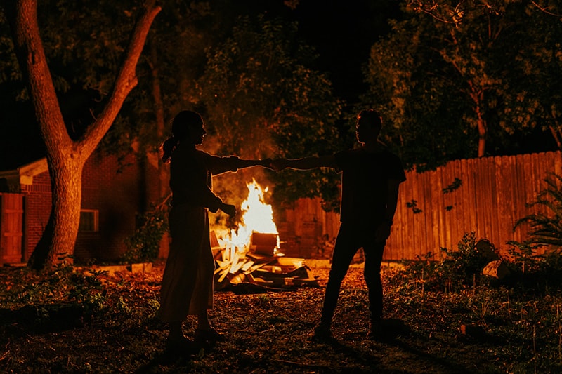 una pareja bailando cerca del fuego en el patio