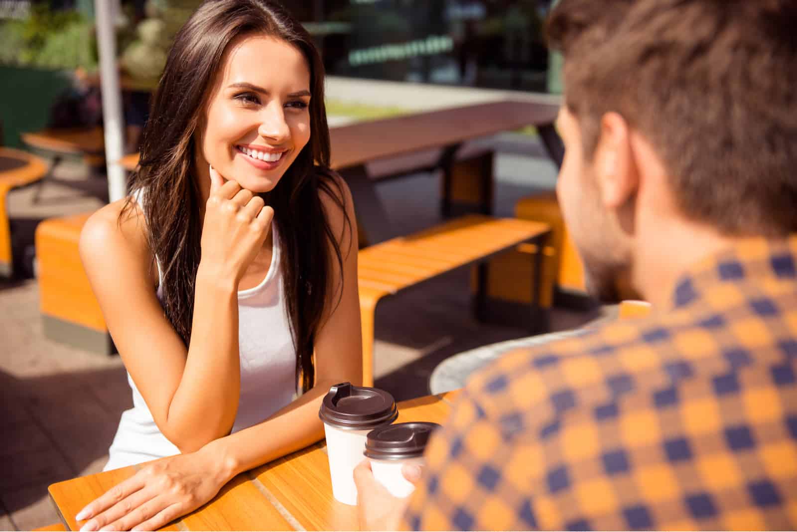 una pareja de enamorados sentados en una mesa al aire libre y hablando