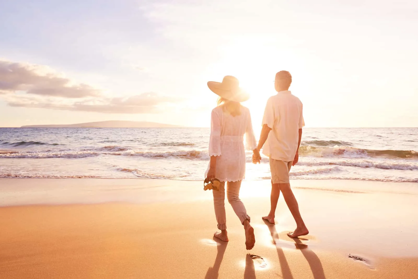 a man and a woman are walking along the beach