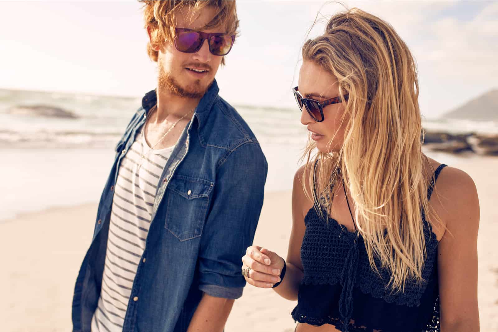 a man and a woman are walking along the beach and talking