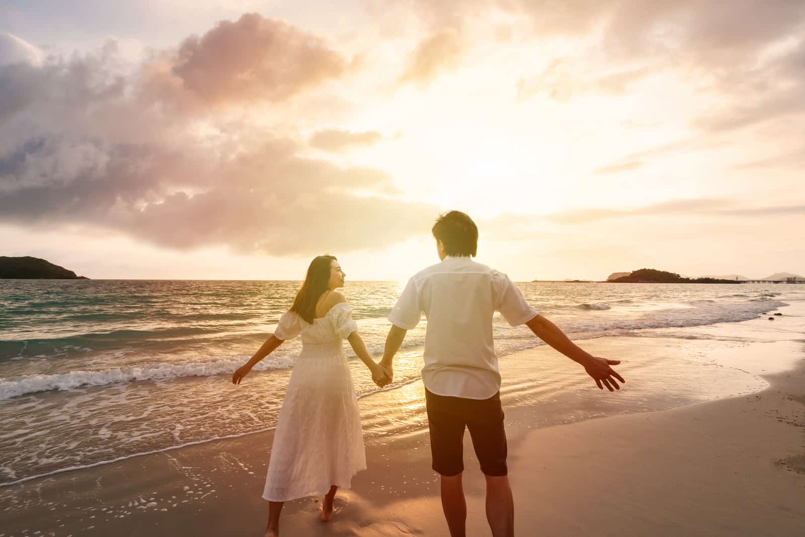 a man and a woman are walking along the beach