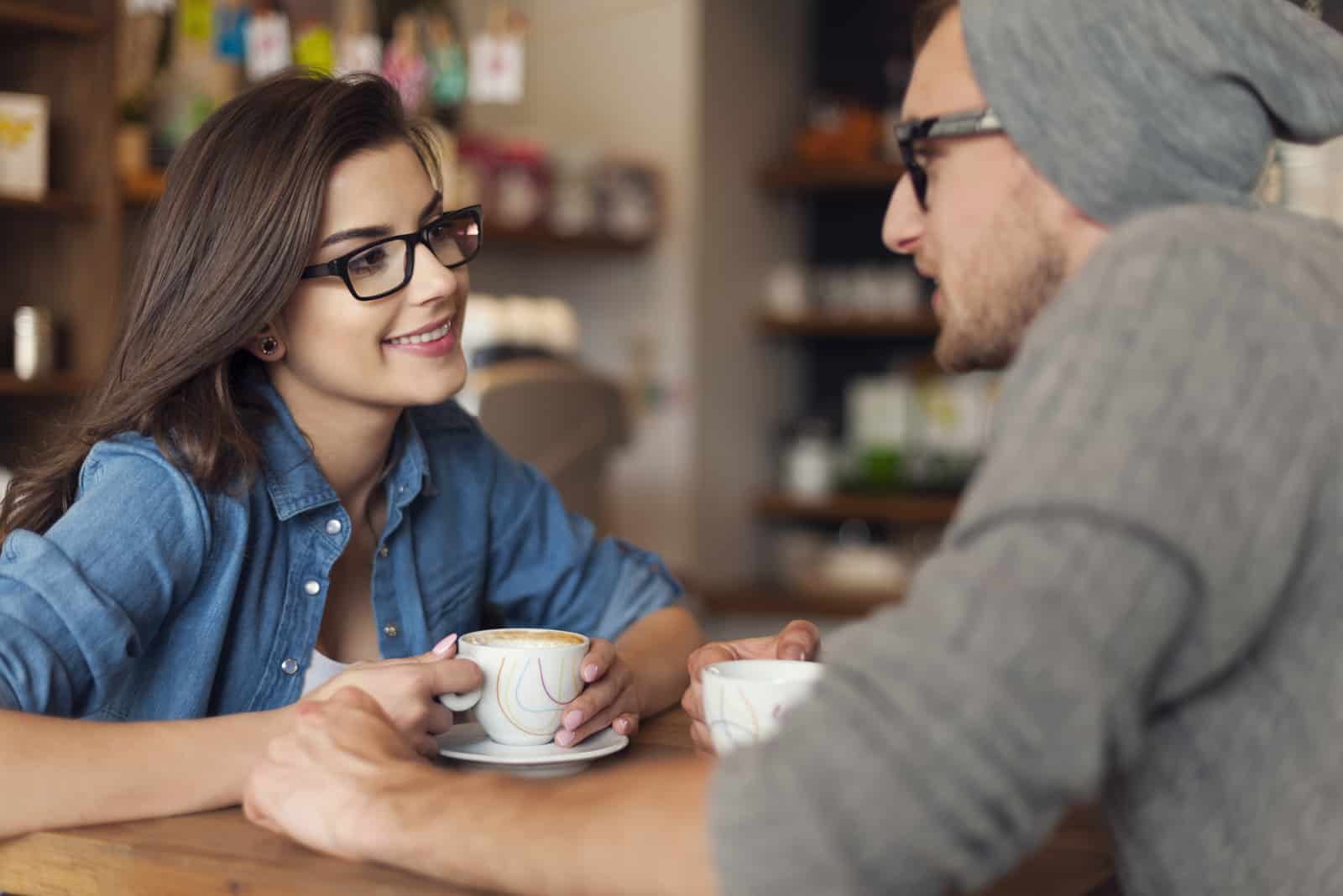 a man and a woman sit at a table and talk