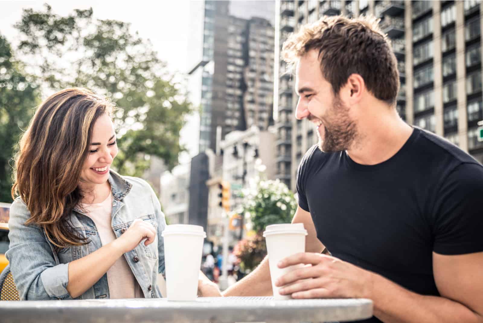 a man and a woman sit at a table and talk over coffee