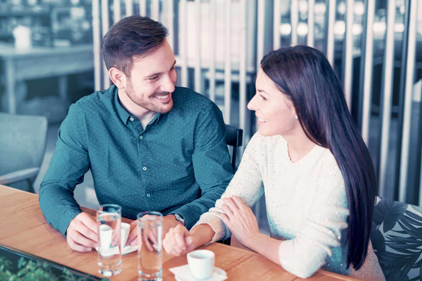 a man and a woman sit at a table and talk