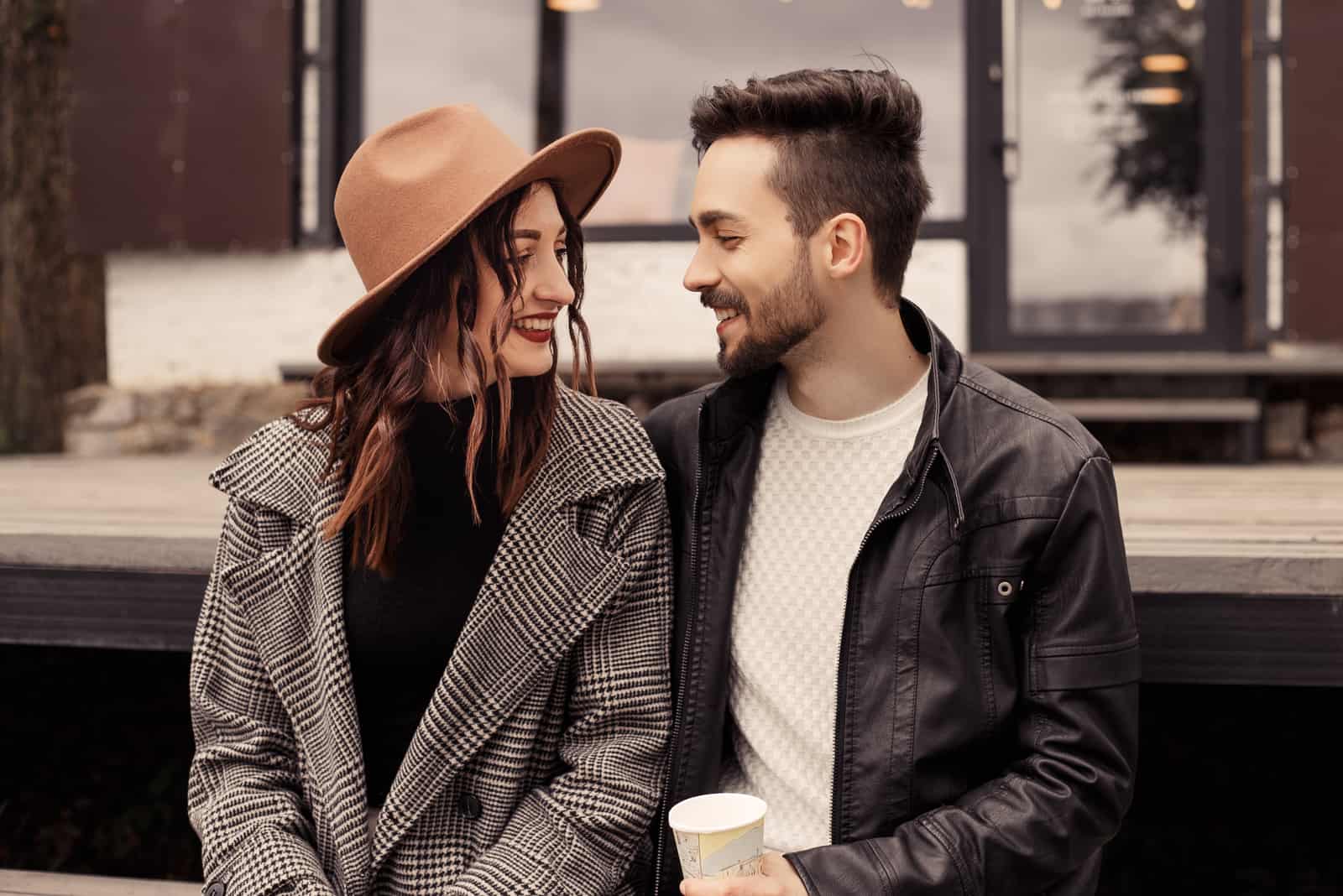 a man and a woman sit on a bench and talk