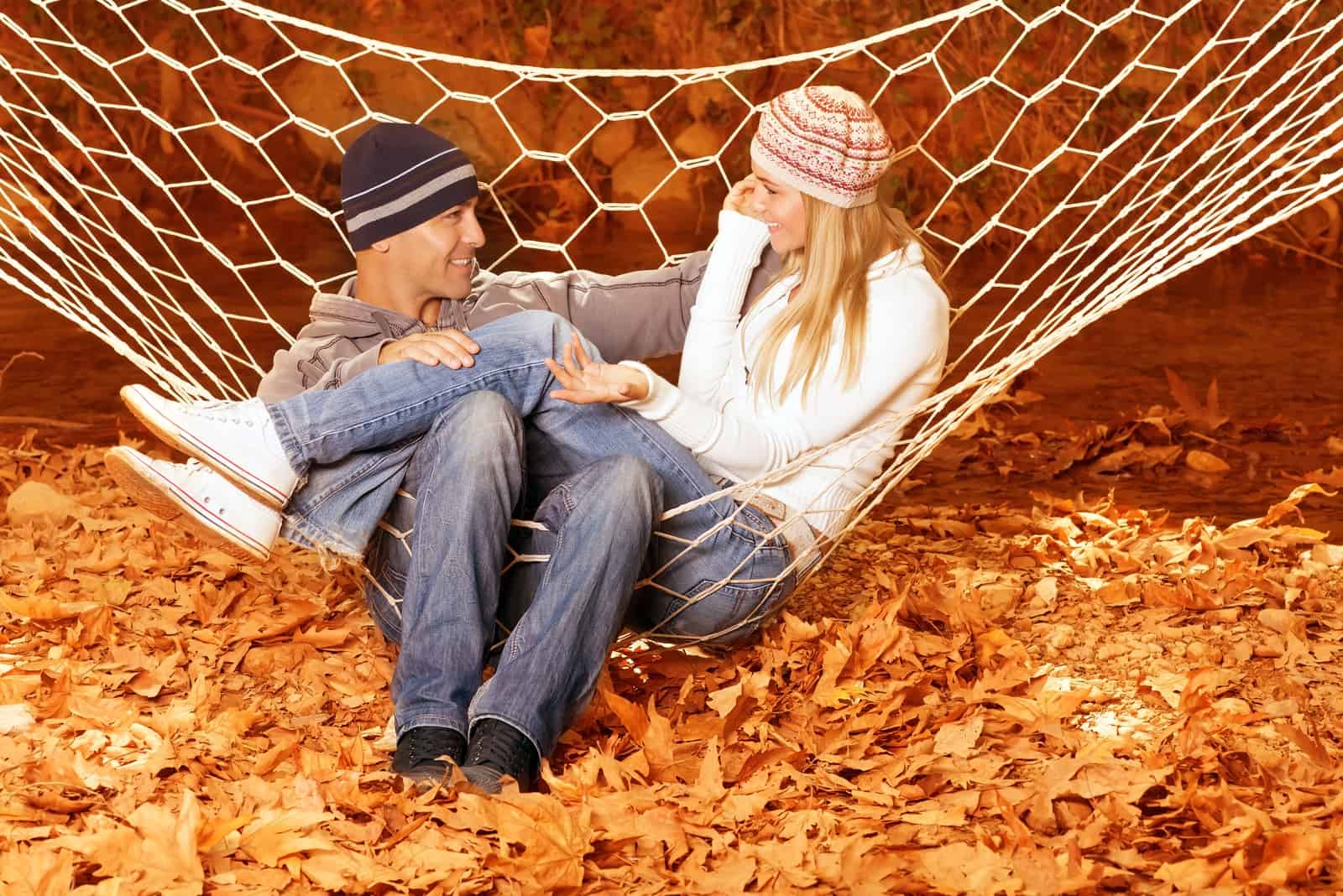 a man and a woman sit on a swing and talk
