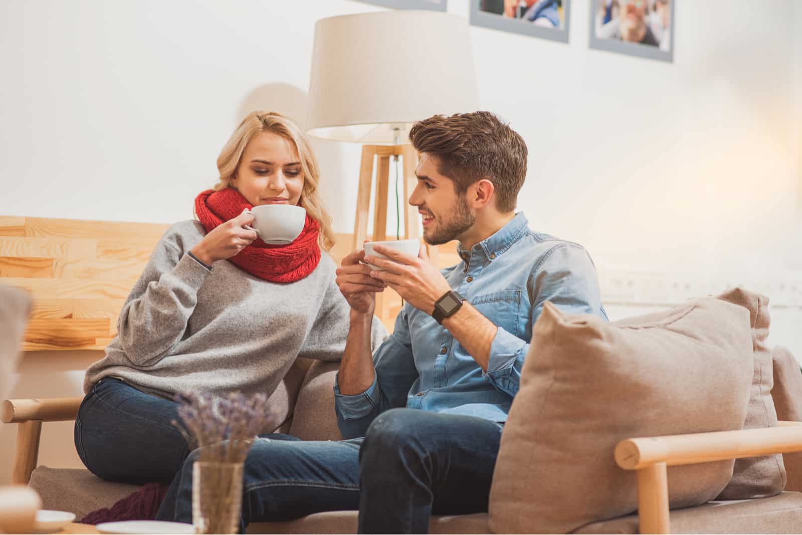 um homem e uma mulher sentam-se no sofá e bebem café