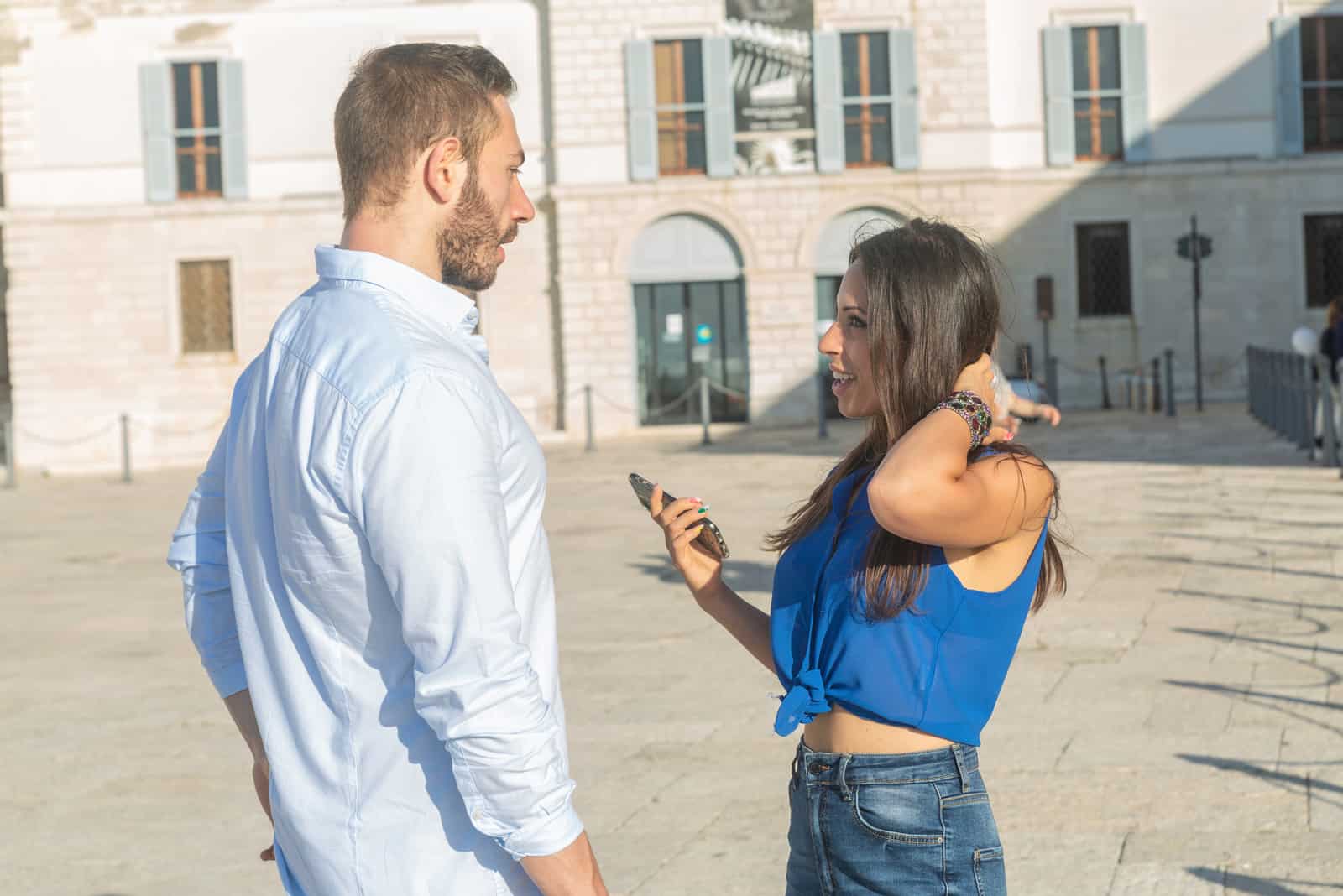 a man and a woman stand on the street and talk