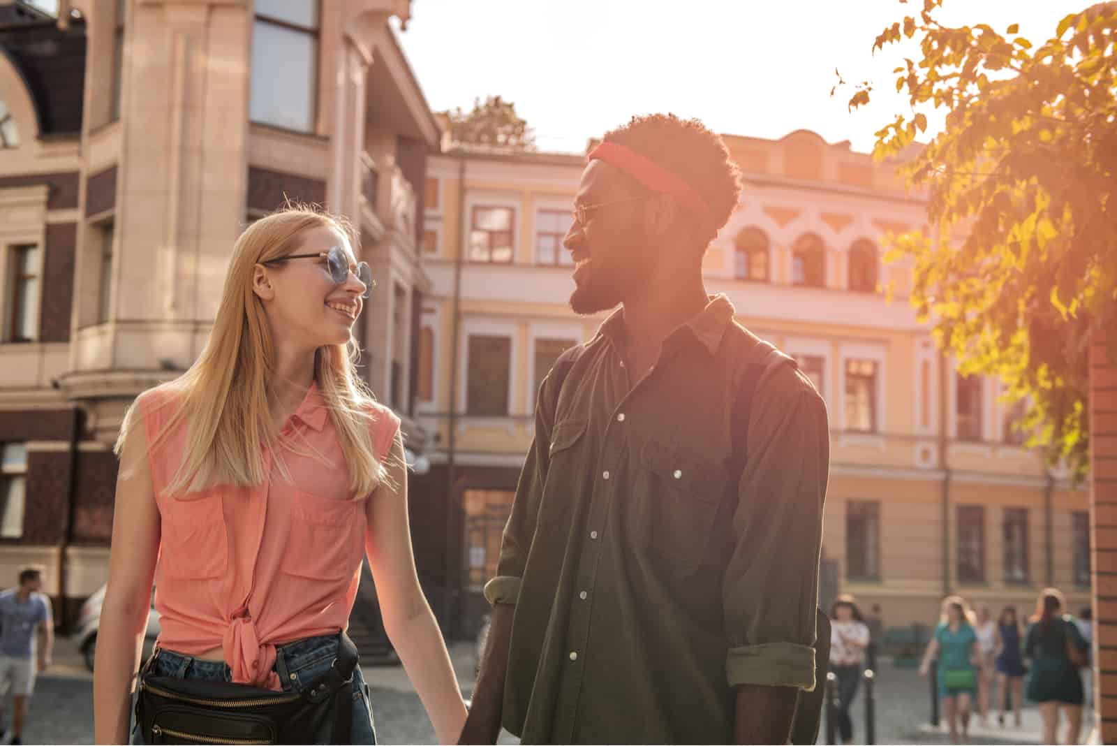 a man and a woman walk down the street holding hands