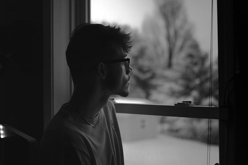 a man standing near the window and looking pensive