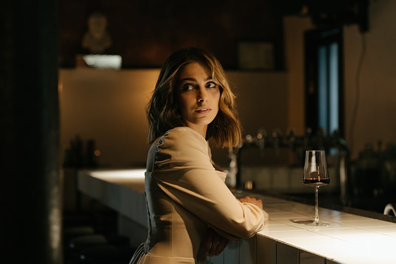 una mujer nerviosa esperando a alguien en el bar y bebiendo vino