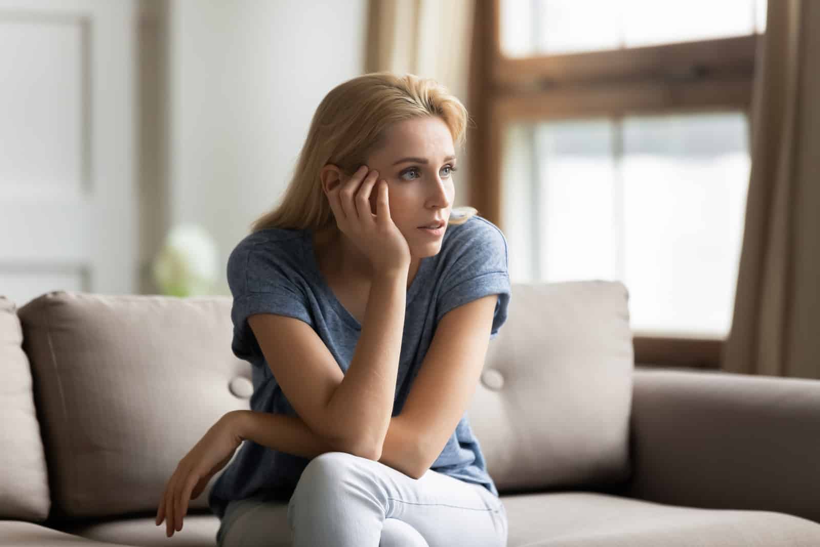 a pensive woman sitting on the couch