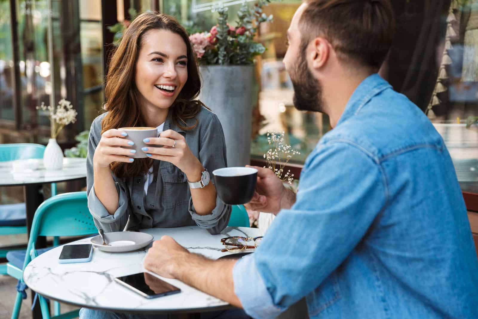 a smiling couple sitting at a table having coffee talking