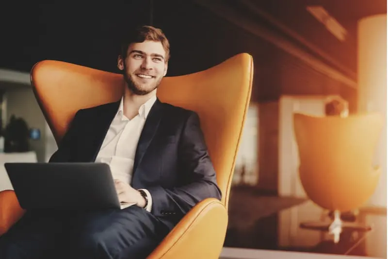 a smiling man sits in an armchair