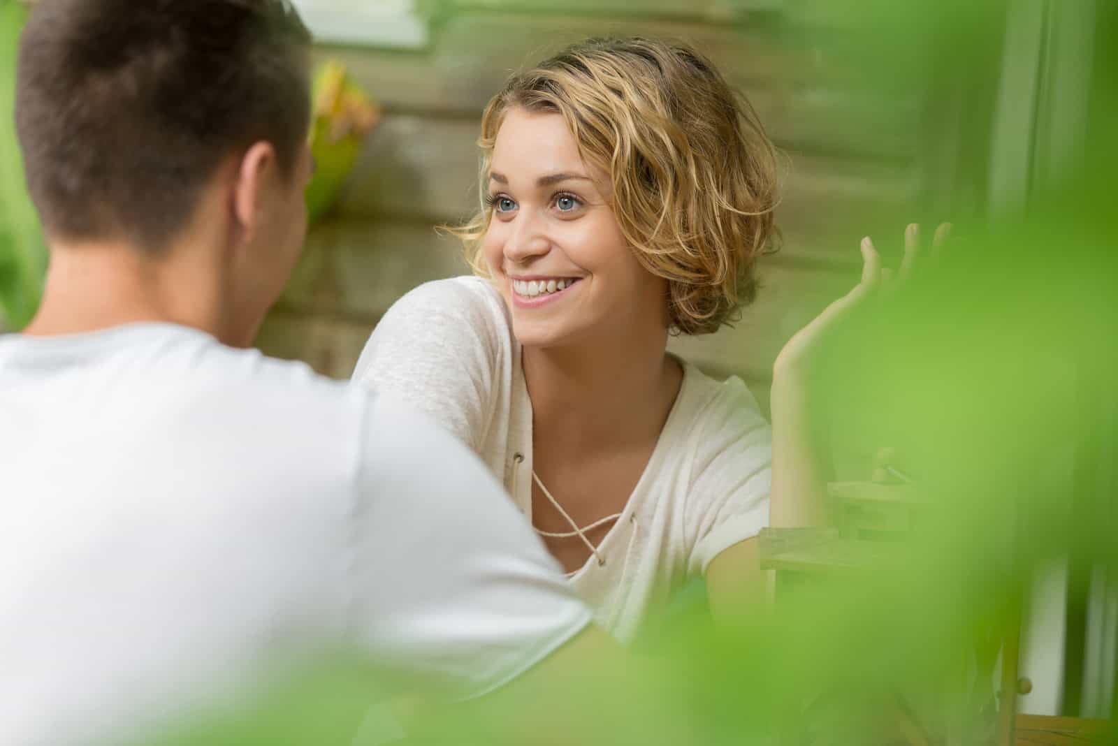 una mujer sonriente hablando con un hombre