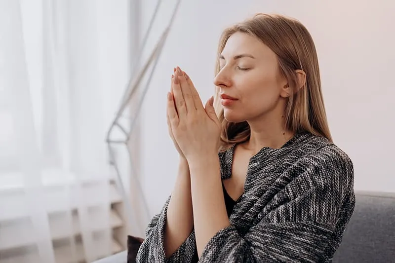 a woman meditating with eyes closed at home