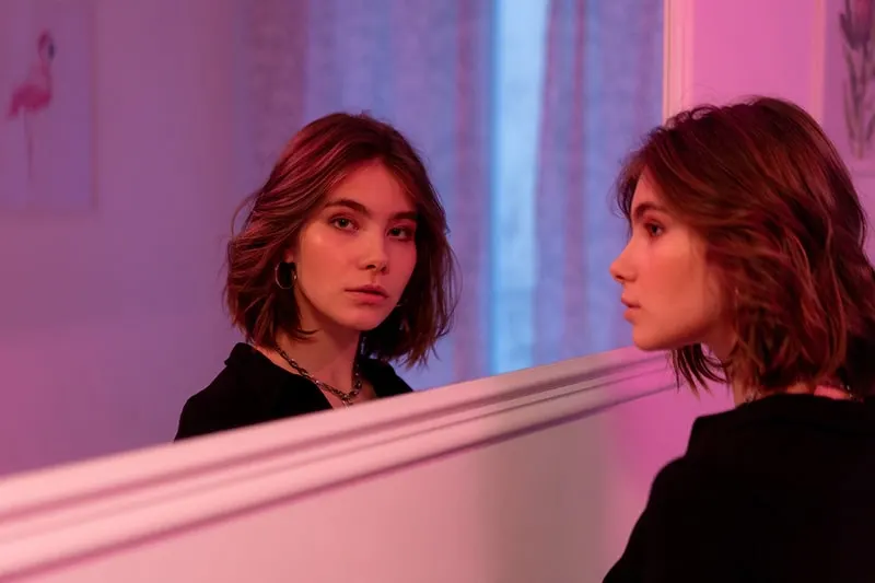 a woman standing in front of the mirror looking thoughtful