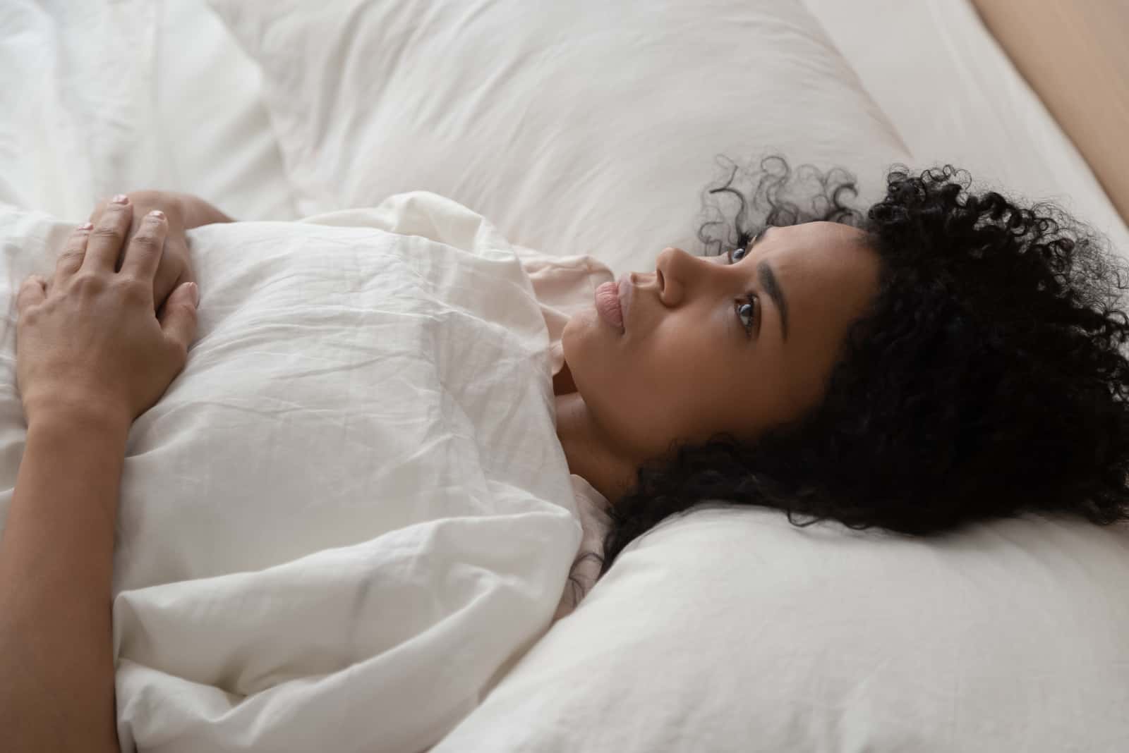 a woman with frizzy hair lies in bed