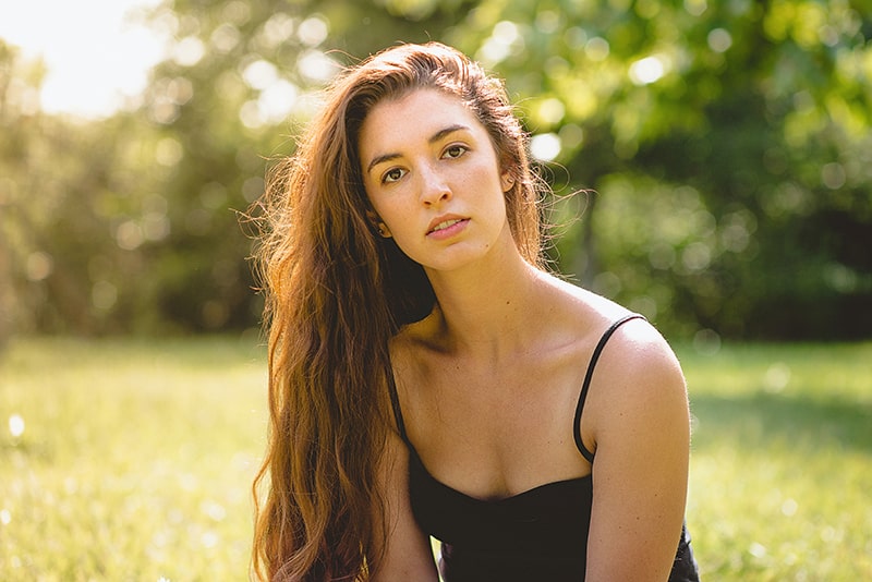 una donna con lunghi capelli castani seduta sull'erba