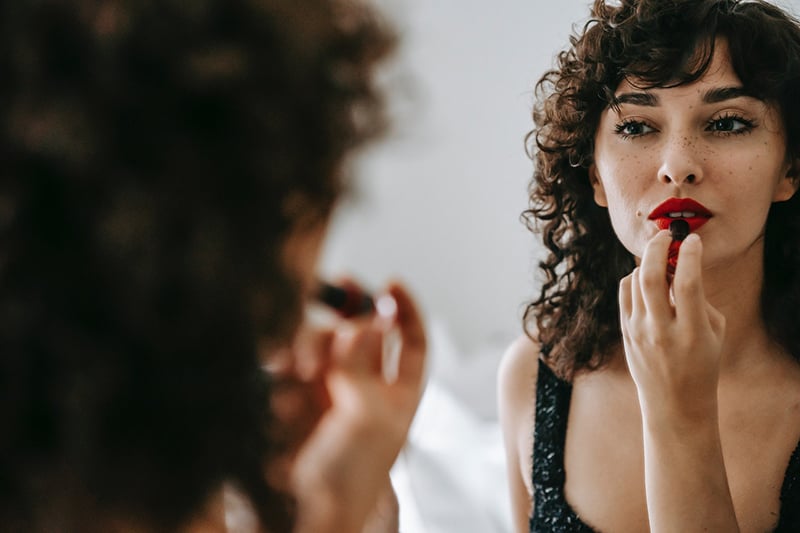confident woman applying a lipstick in front of the mirror