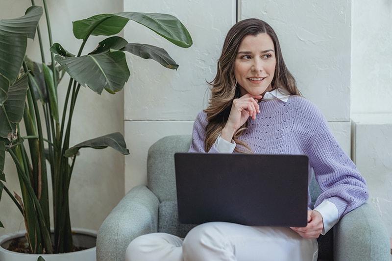 confident woman working on laptop sitting in armchair