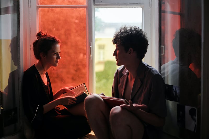 couple discussing a book while sitting on a windowsill