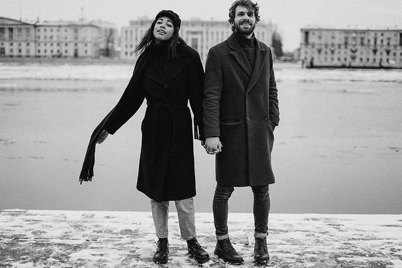 couple holding hands standing near the river